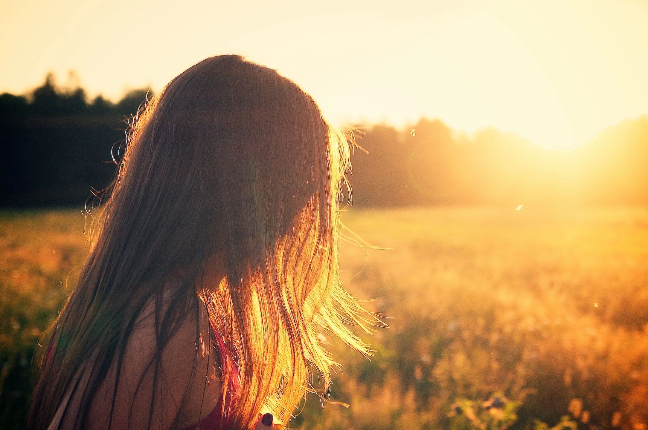 long haired child looking across a field at dusk